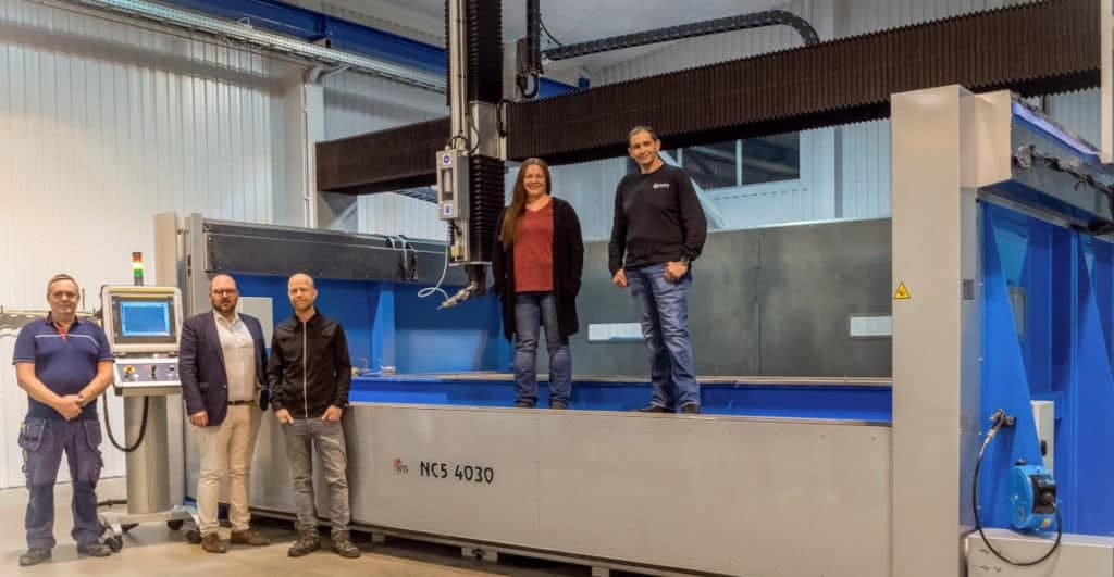 Stående på maskinen: Radius Aerospace-teamet med projektledaren Elizabeth Robinson. Water Jet Swedens team på golvet med US sales manager Christian Svensson i mitten. Foto: Water Jet Sweden